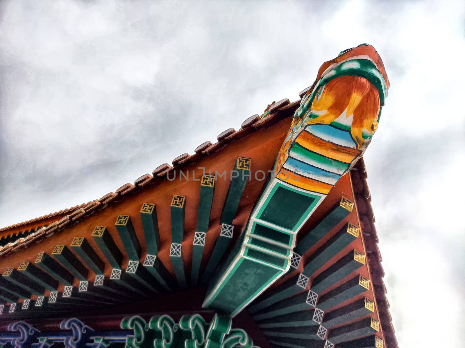 The vibrant eaves of an ornate temple roof showcase stunning craftsmanship against a moody sky.