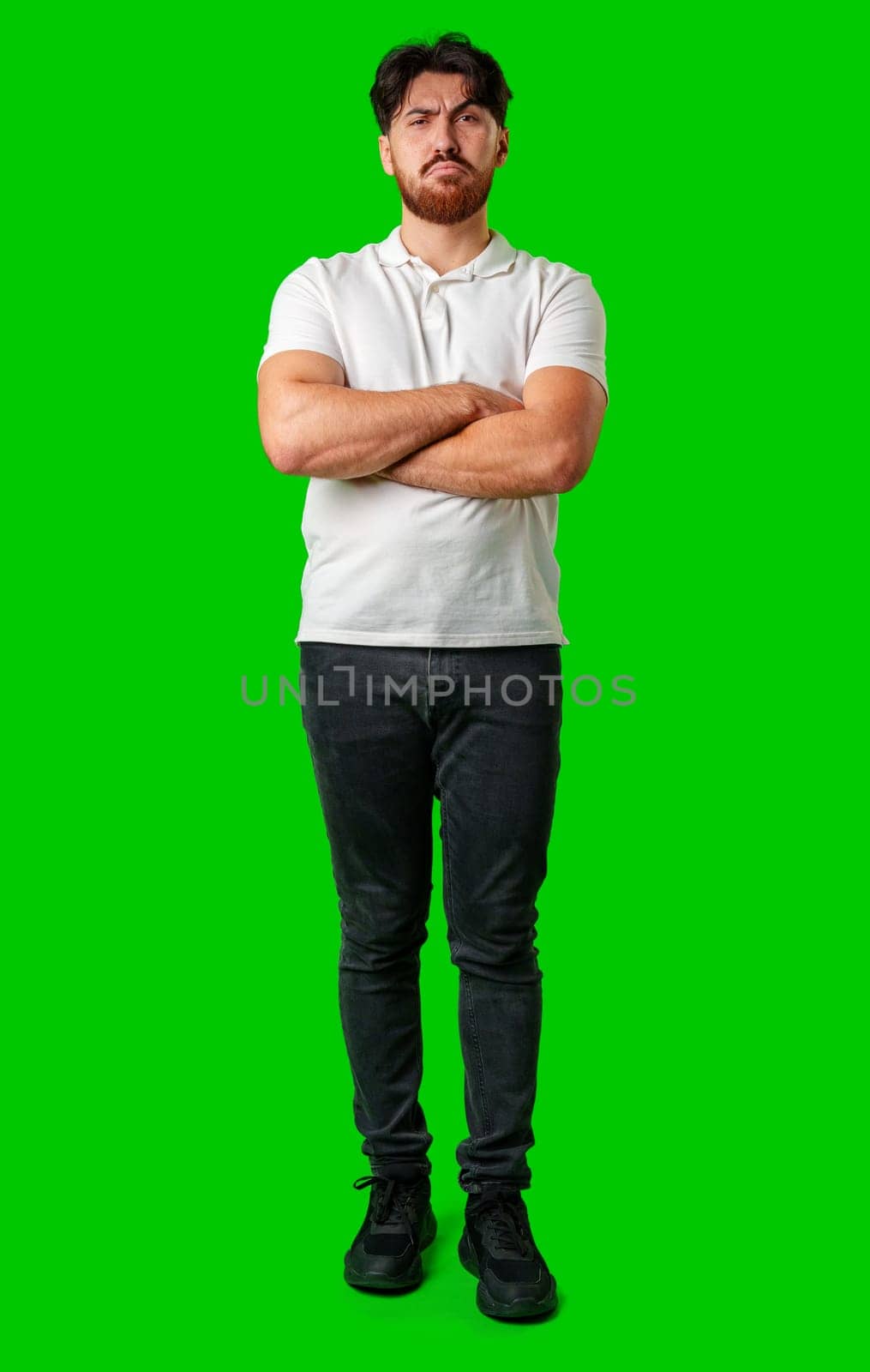 A young man with a beard showing a serious expression against a vibrant green background close up