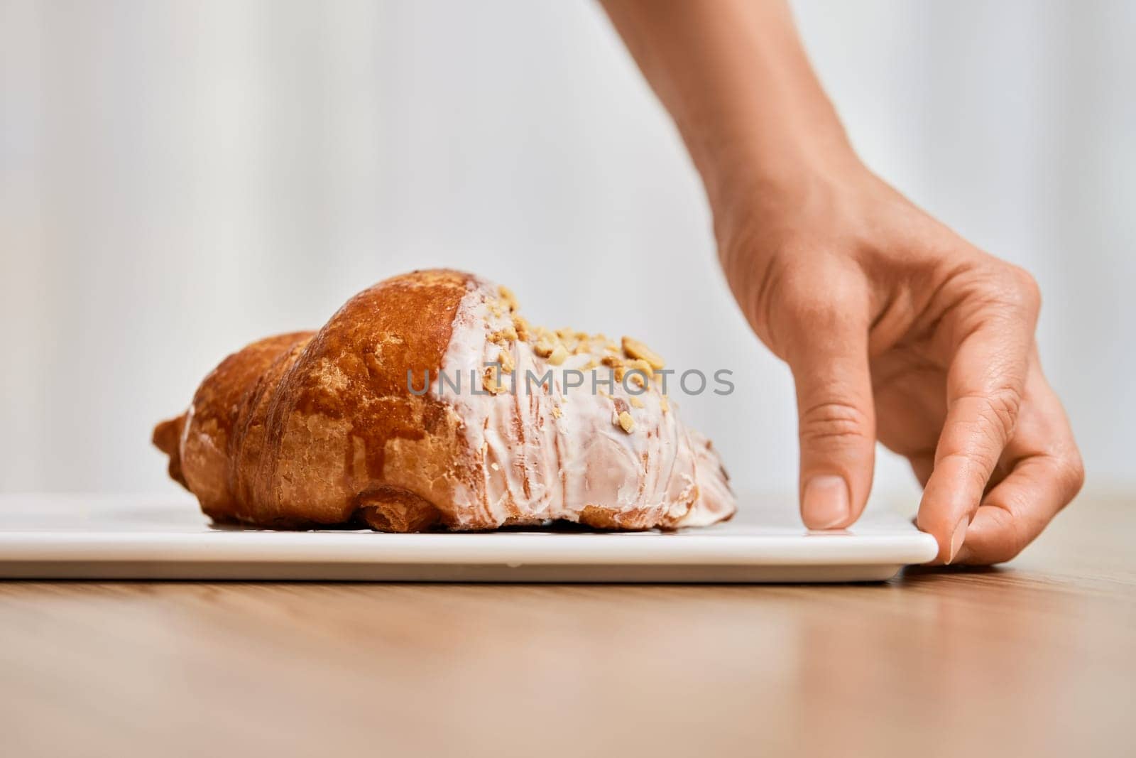 female hand holding fresh handmade croissant on white plate