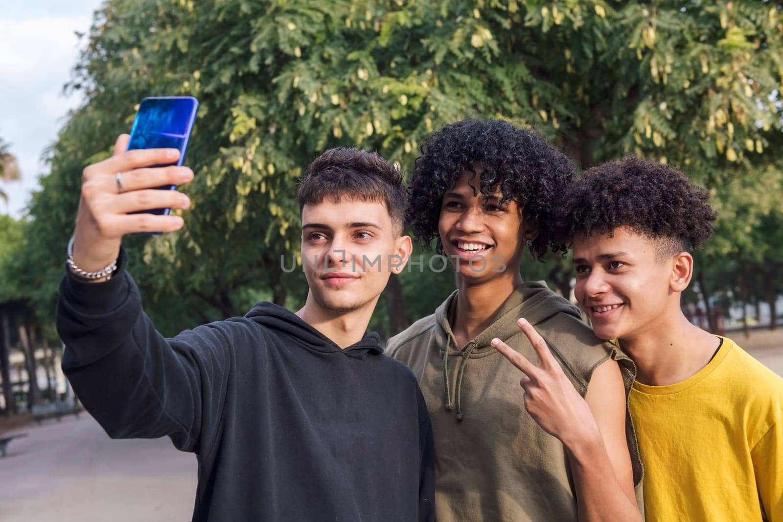 multiethnic group of three male teens smiling happy taking selfie photo with mobile phone, concept of youth lifestyle and technology of communication