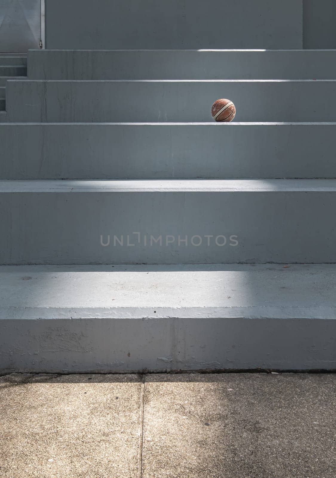 Old basketball ball on cement floor with Stairs leading and Natural light. use it as your Wallpaper, Poster and Copy space, Selective focus.