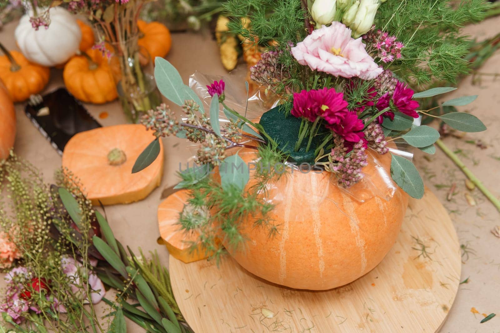 Flower arrangement in a pumpkin, autumn interior decor. Creating handmade autumn decor