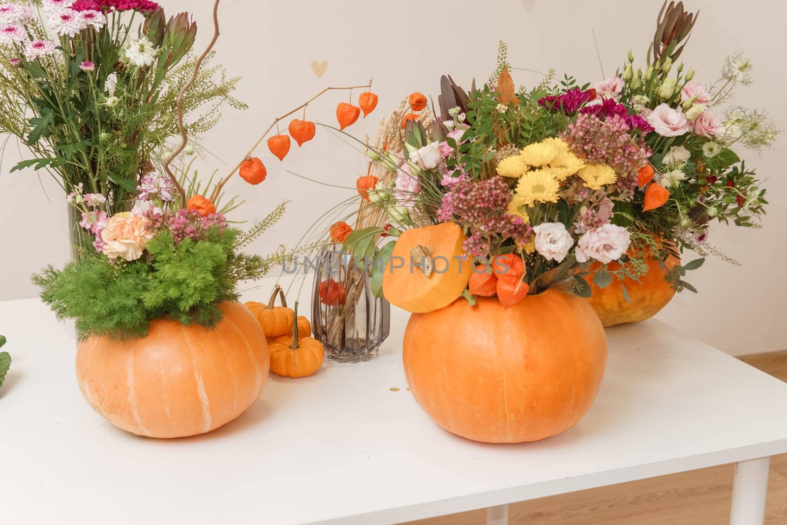 Flower arrangement in a pumpkin, autumn interior decor. Creating handmade autumn decor