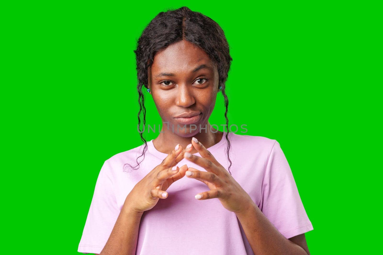 Young woman with curly hair shows a skeptical expression against a bright green background in studio