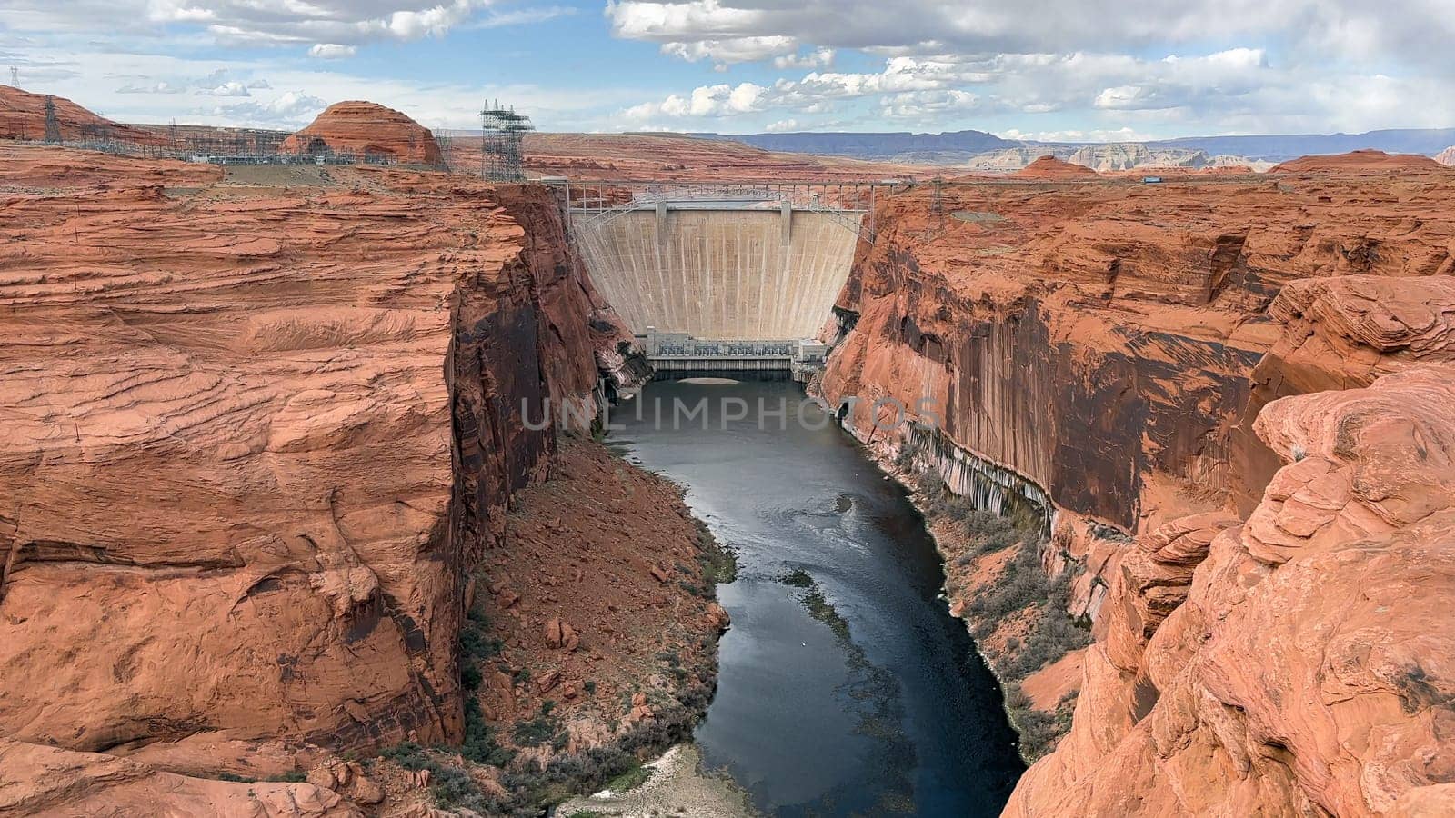 View of Glen Canyon Dam and the Colorado River from the overlook on Highway 89 in Page, Arizona, USA. Showcasing the impressive scale of the dam and the beauty of the surrounding red rock canyon.