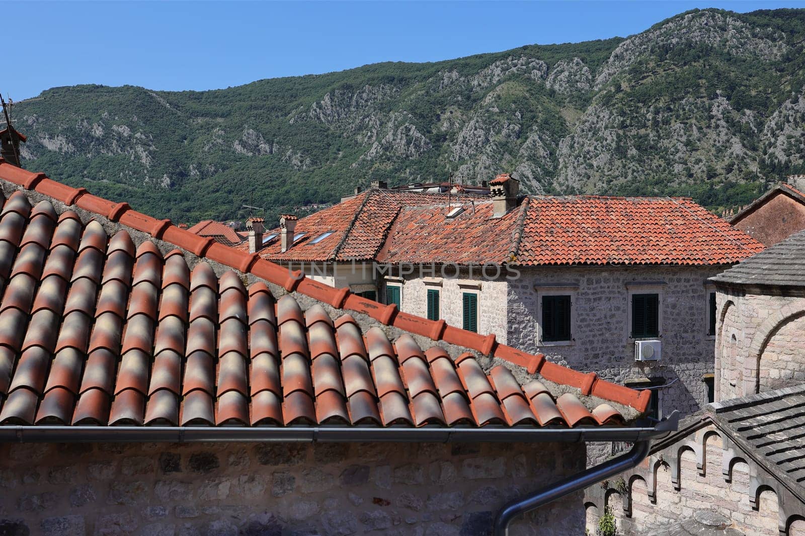 Roof texture seamless, roofs of houses covered with old natural tiles against the backdrop of the sky and mountains.