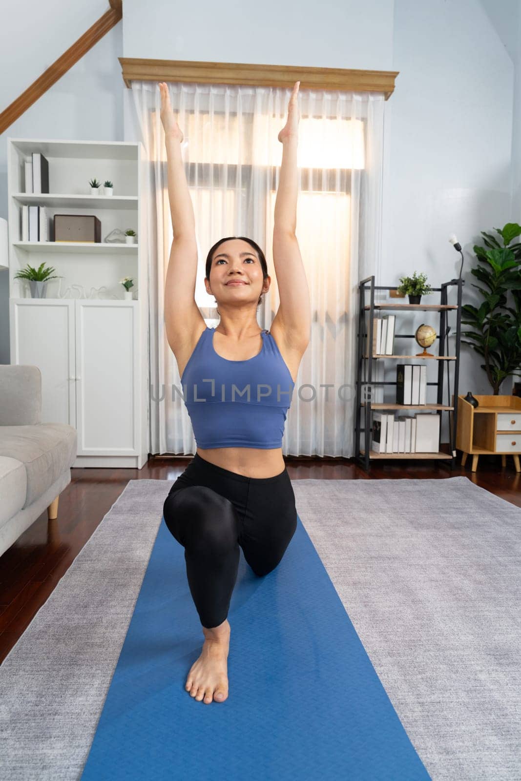 Asian woman in sportswear doing yoga exercise on fitness mat. Vigorous by biancoblue