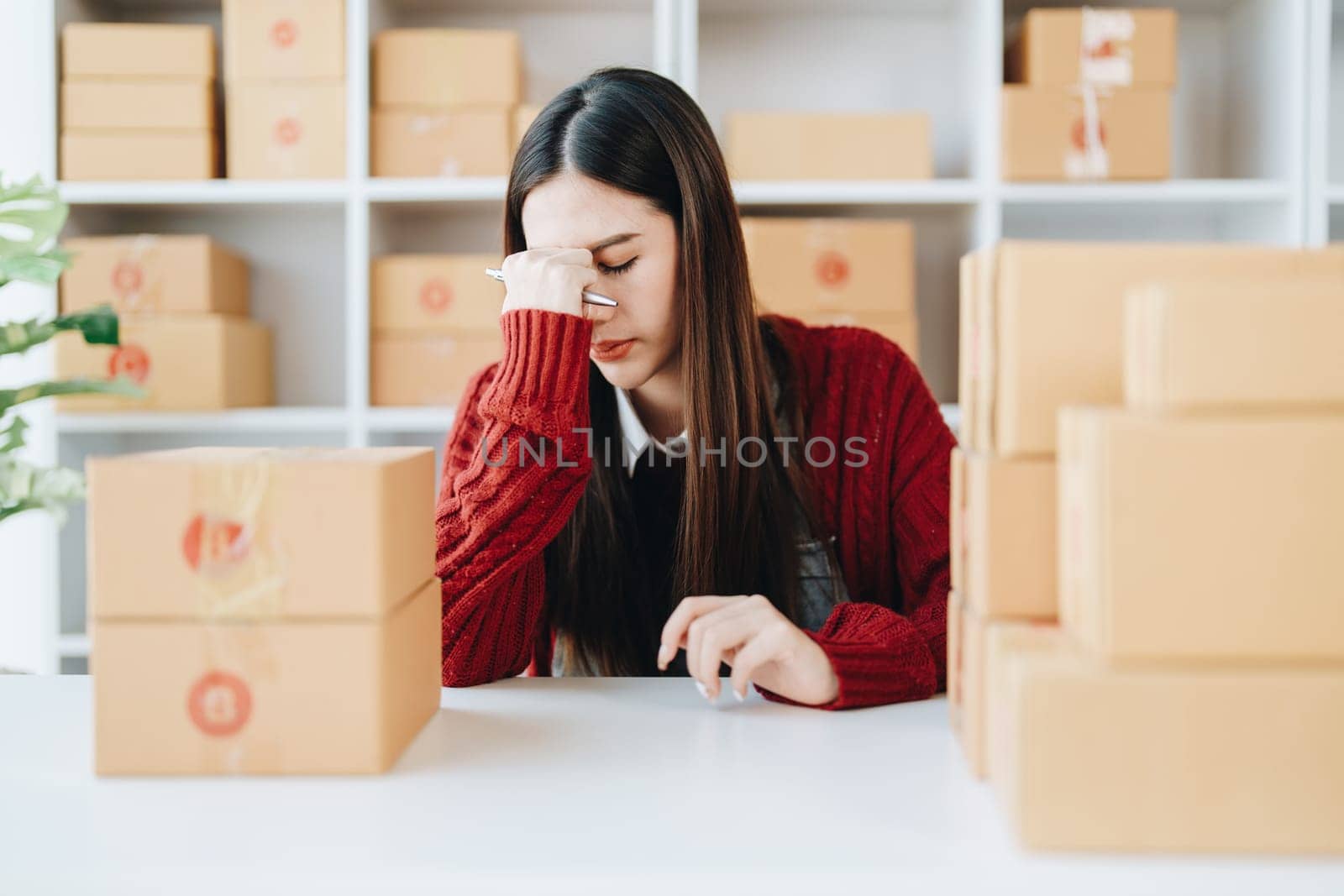 Starting small business entrepreneur of independent Asian woman showing her face worried about the sales of her business not reaching the target set. SME concepts.