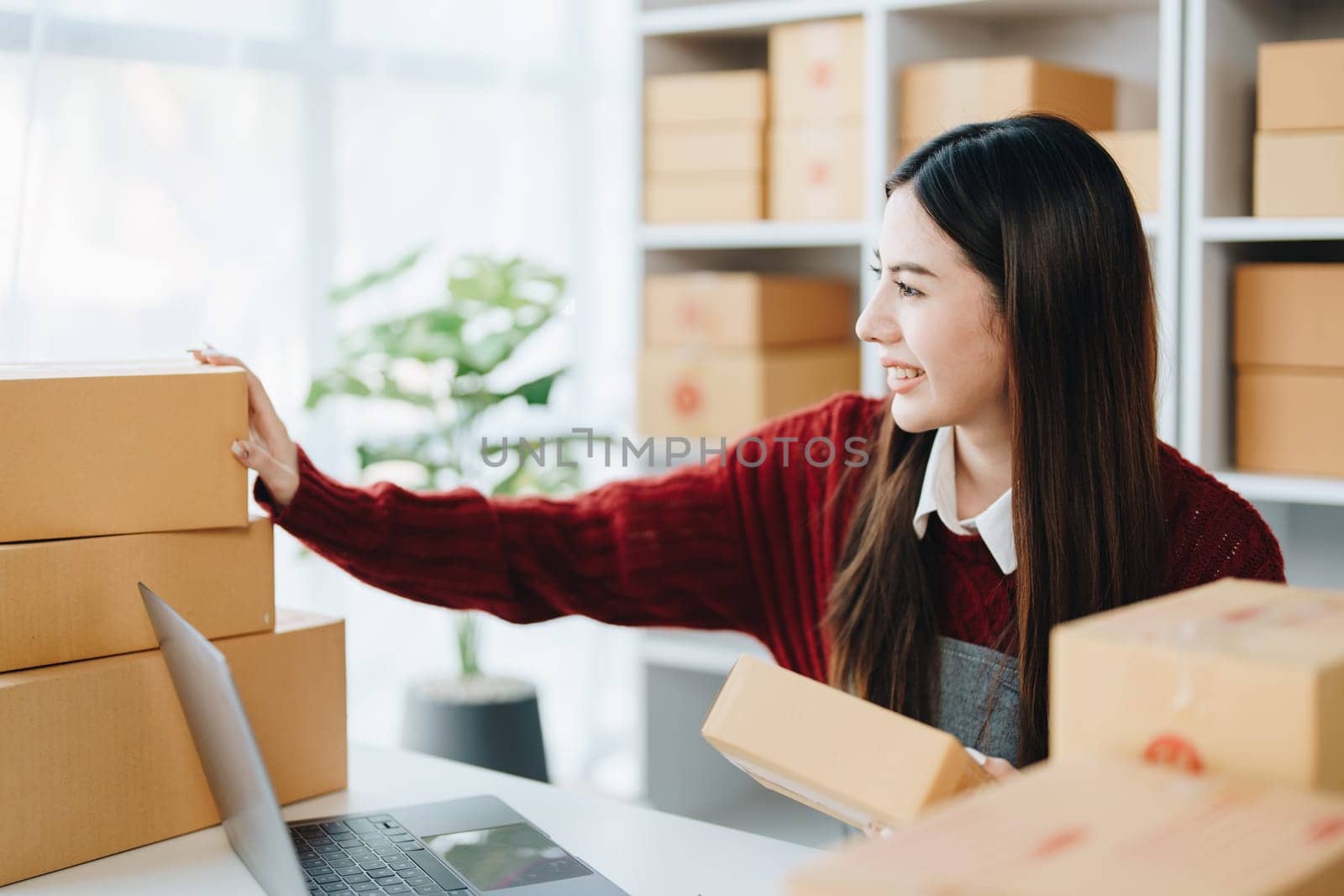 Asian female business owner handles delivery of orders to customers by Manastrong