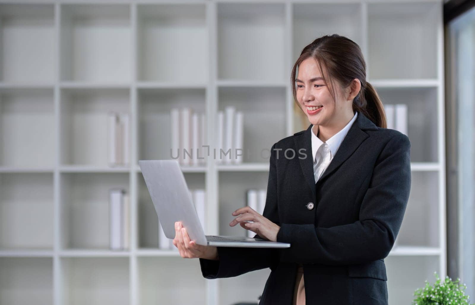 Portrait of a young business woman standing holding a laptop and focusing on the work she is about to do..
