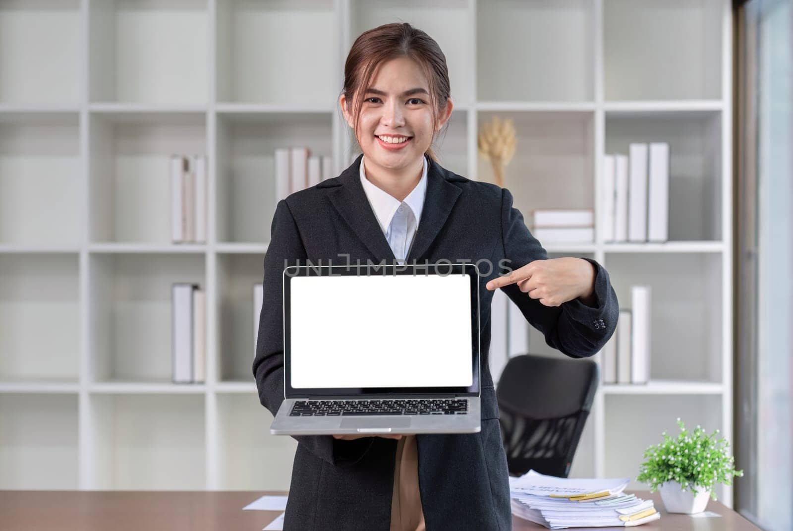 Pointing Pilot. Young business woman standing holding laptop and focusing on work being done on laptop..