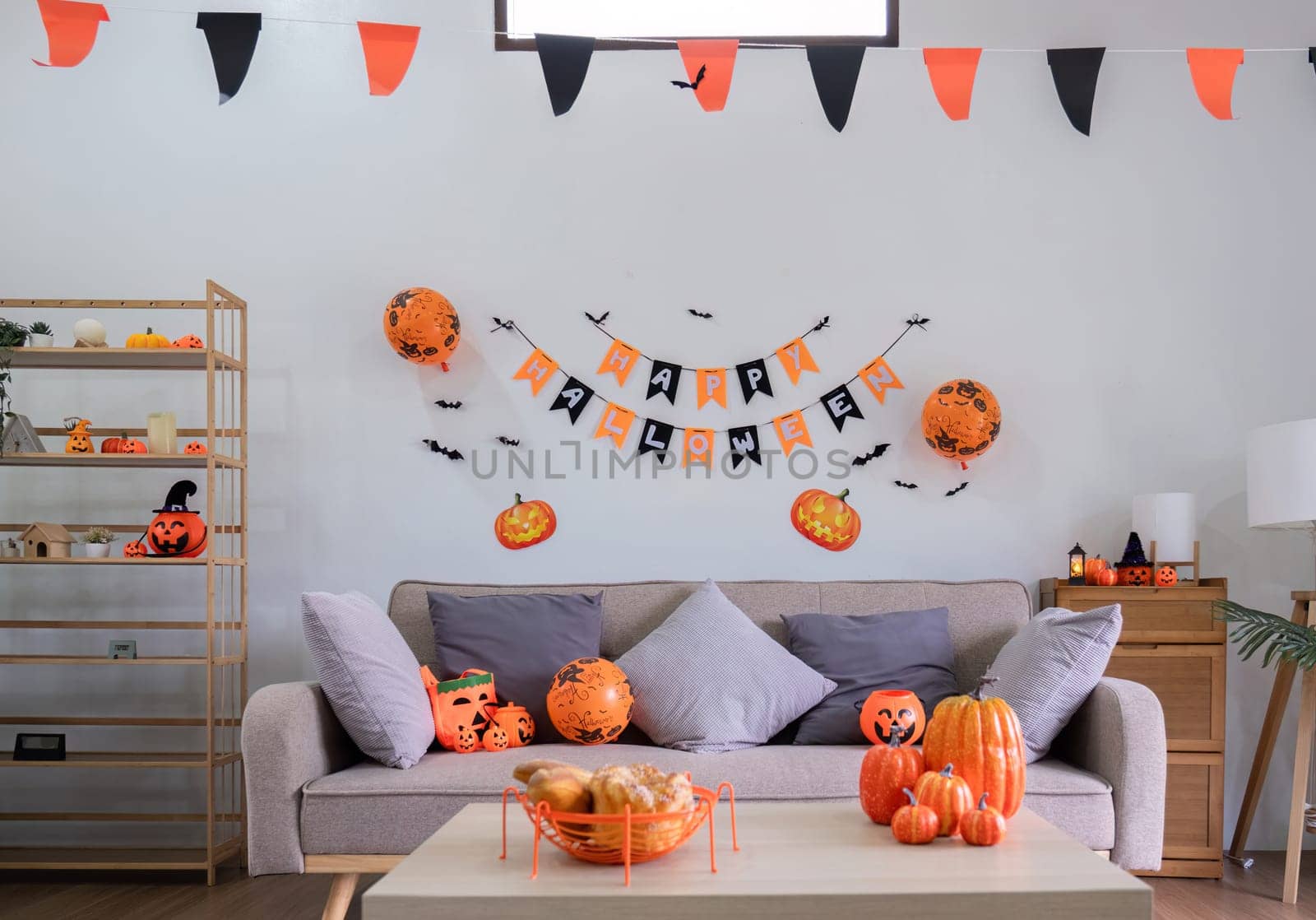 title Halloween background. An orange pumpkin placed on a wooden table in the living room. Festive home decorating ideas. by wichayada