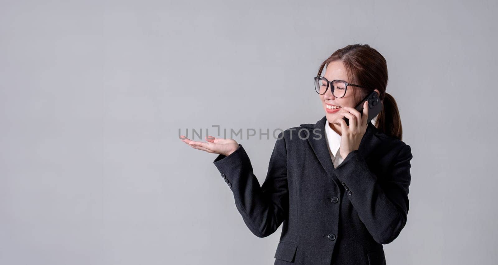 Portrait of a young business woman standing and talking on the phone, pointing, focus according to thoughts..