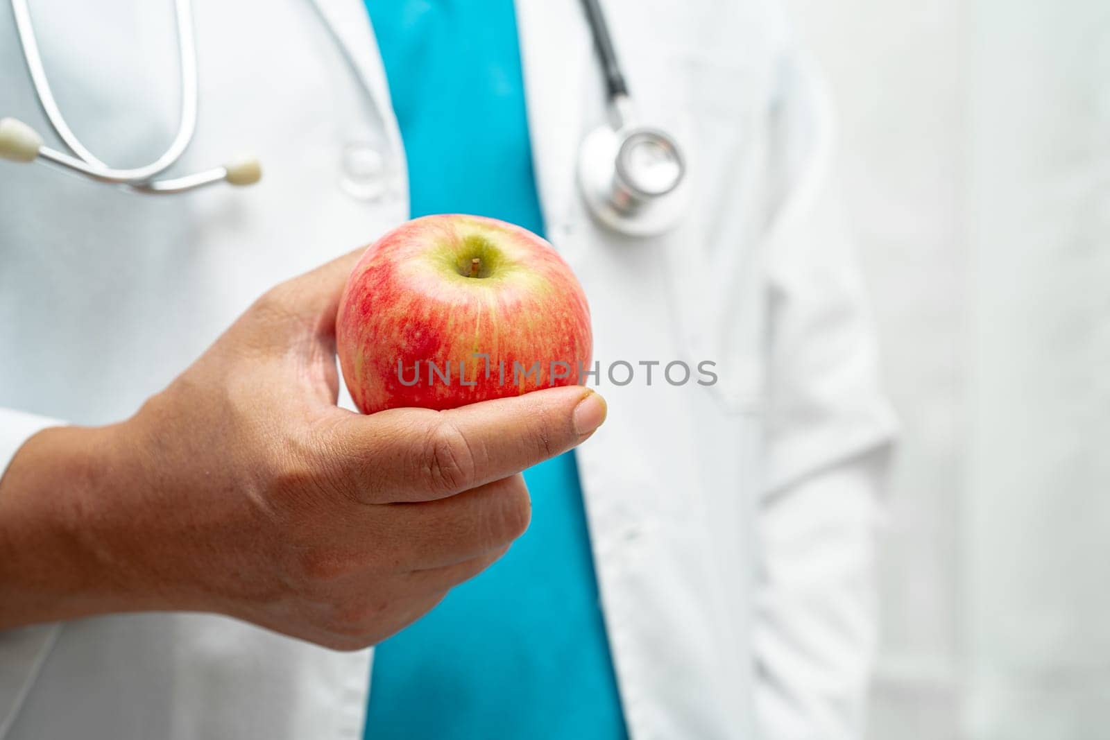 Doctor holding apple fruit vitamin food for healthy patient in hospital.    by pamai