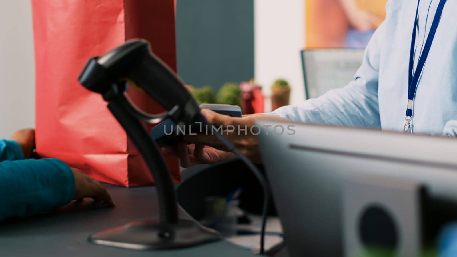 African american woman paying for stylish clothes with credit card using payment terminal during shopping session in modern boutique. Customer buying formal wear in clothing store. Fashion concept