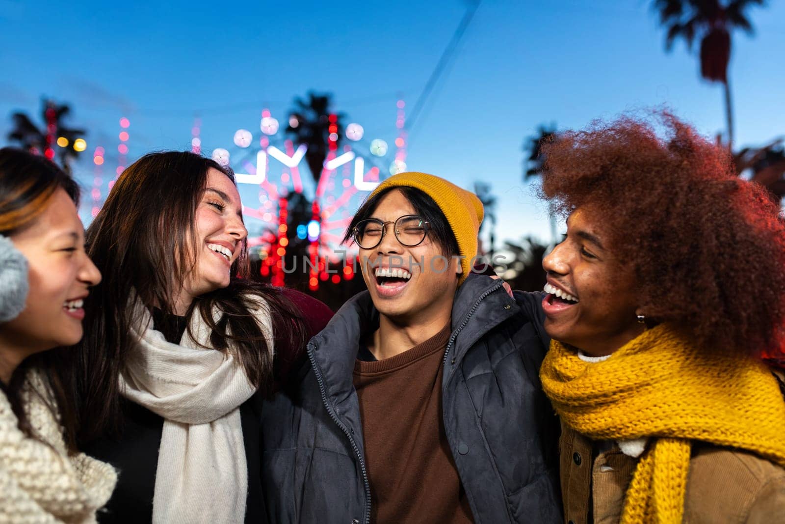 Multiethnic university friends laughing and having fun together during winter Christmas market outdoors. by Hoverstock