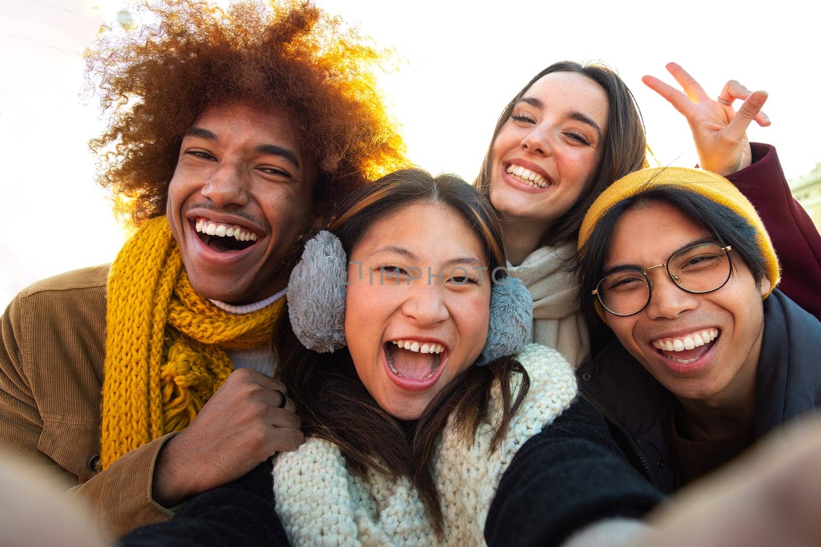 Happy and cheerful multi-ethnic college friends having fun outdoors. Multiracial young group of people taking selfie looking at camera.Gen z, friendship and technology concept.