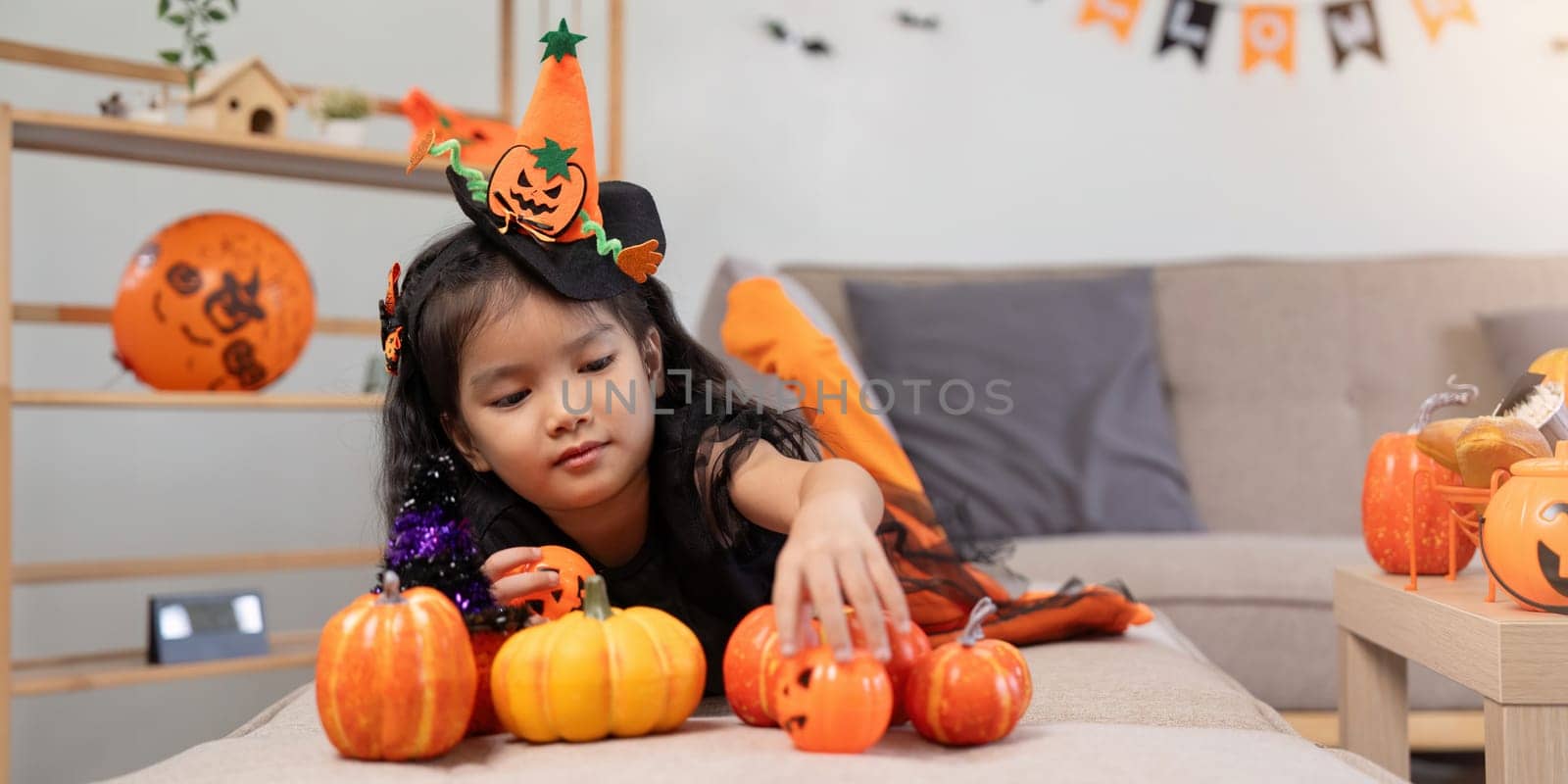 Cute little child girl with pumpkin balloon. Happy family preparing for Halloween by nateemee