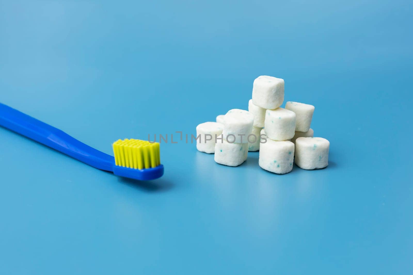 Bunch Of Healthy Sugar-Free Xylitol Cubes Of White Chewing Gum, Toothbrush on Blue Background. Healthy Teeth, Beautiful Smile Concept. Top View, Copy Space. Heap of Bubble Gum. Horizontal Plane. by netatsi