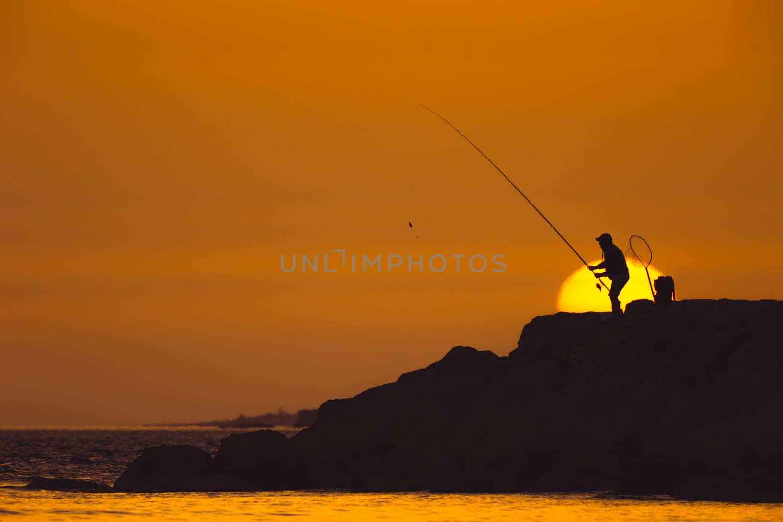 A man is fishing at sunset. Mid shot