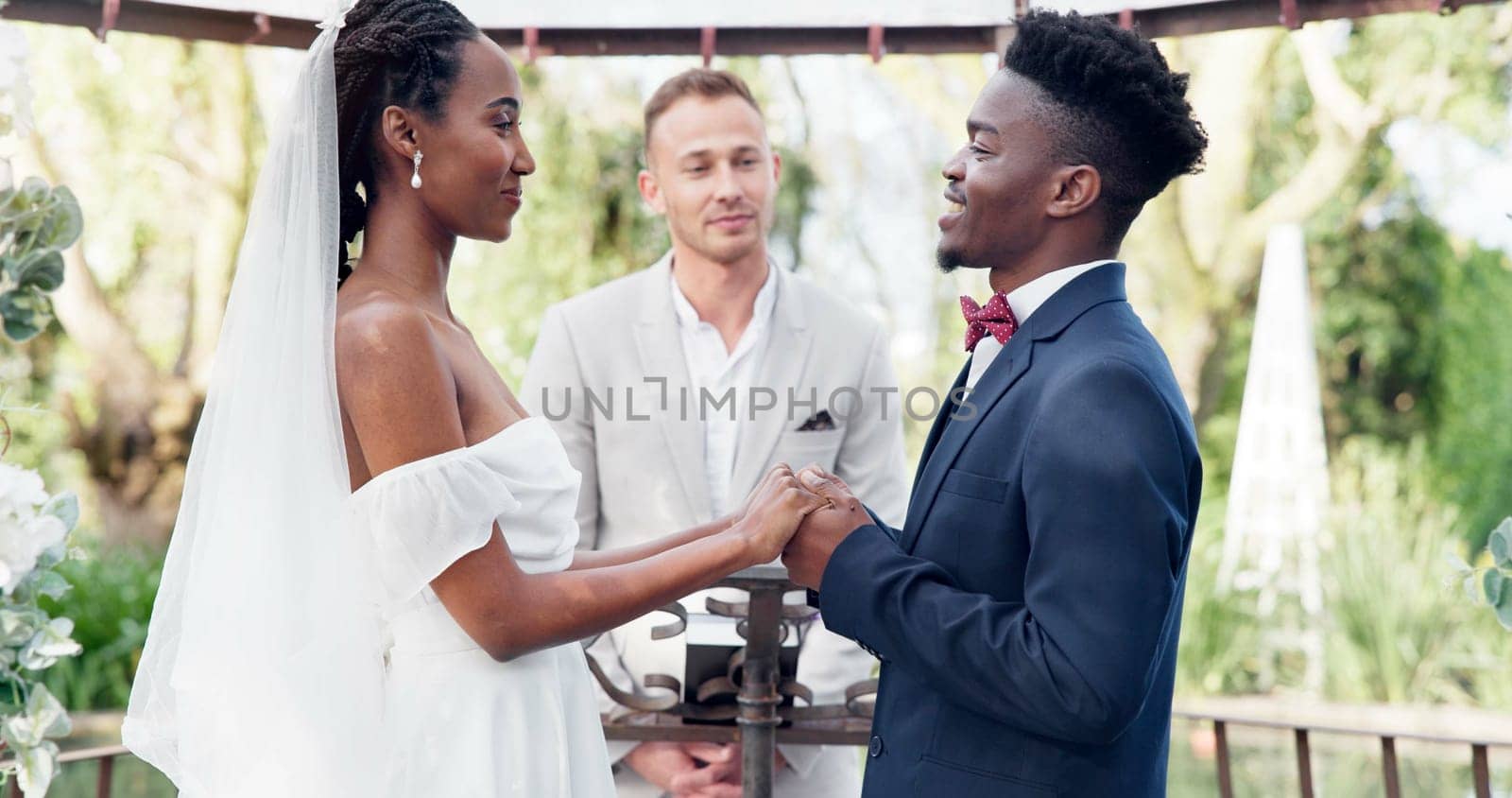 Happy black couple, wedding and vows in marriage, commitment or support together at alter. Married African woman and man holding hands for love, trust or speech of bride or groom in outdoor romance by YuriArcurs