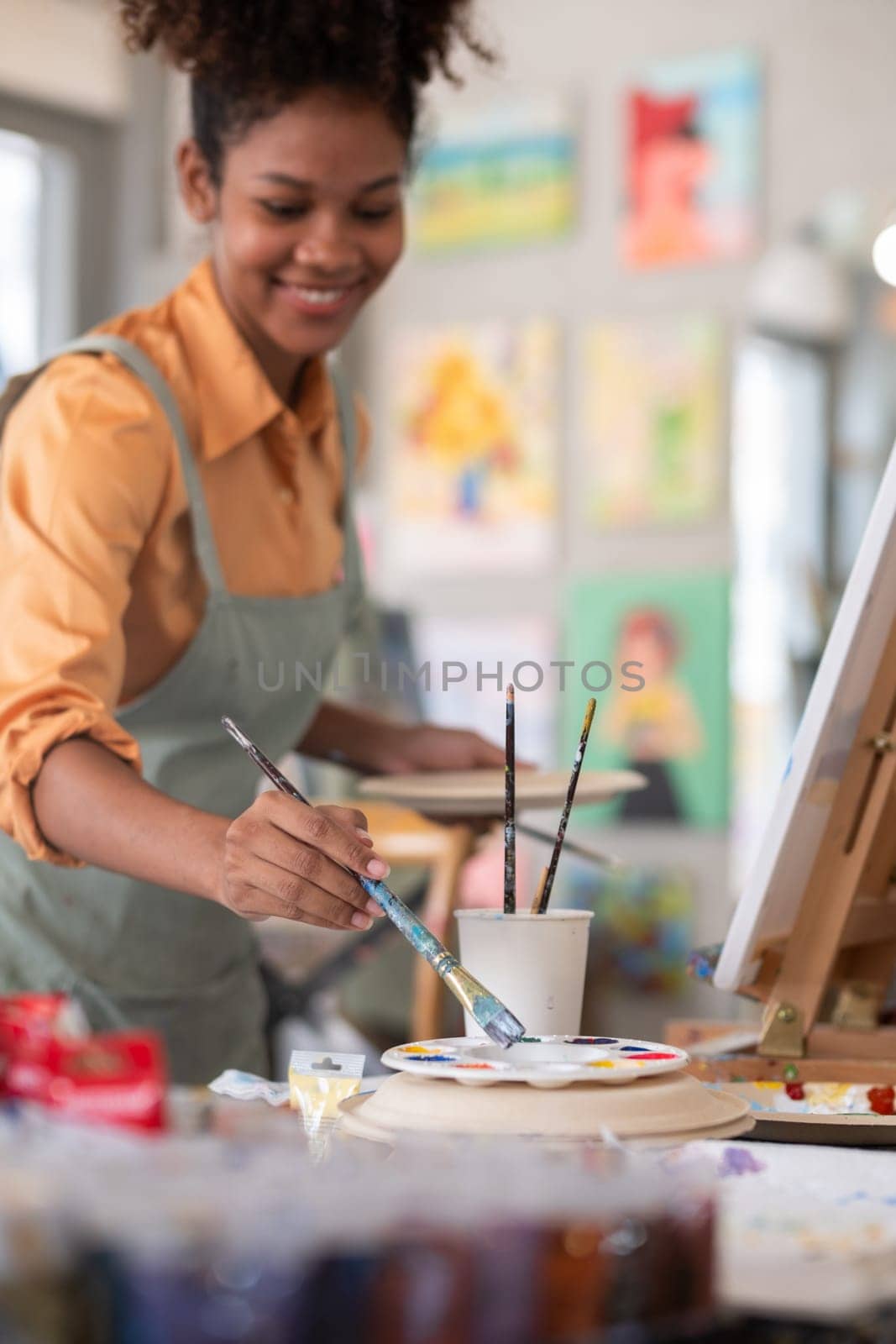 Portrait of a female African artist working on several art projects in her studio with great enjoyment. by wichayada