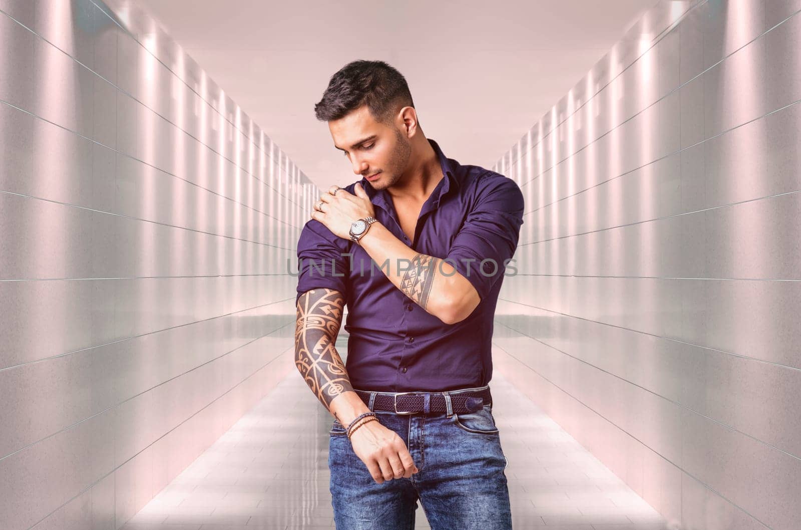 A man with tattoos standing in a hallway