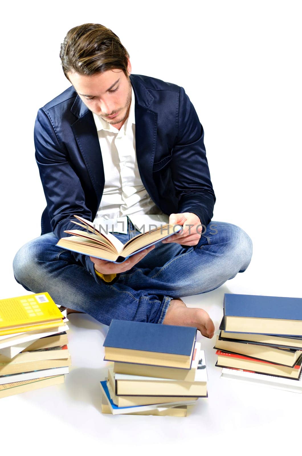 Young adult reading publication, sitting on white background in casual clothing and jeans. by artofphoto