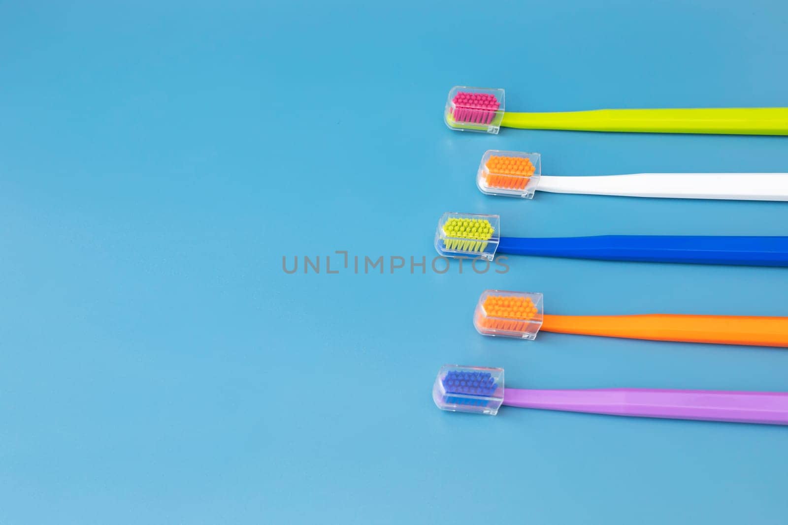 Design Flat Lay Multicolor Toothbrushes on Blue Background, Copy Space. Oral Hygiene, Dental Care, Heathy Tooth And Smile. Sustainable Mouth Product. Horizontal Plane by netatsi