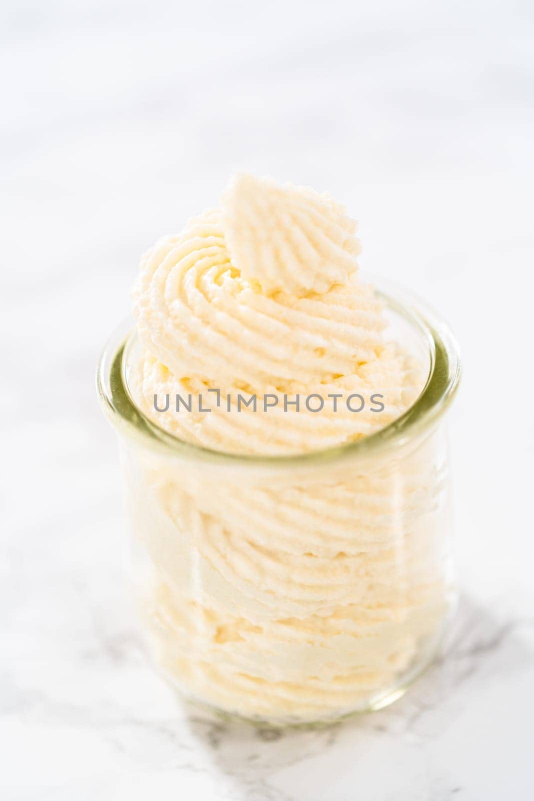 White chocolate ganache frosting in a small glass mason jar.