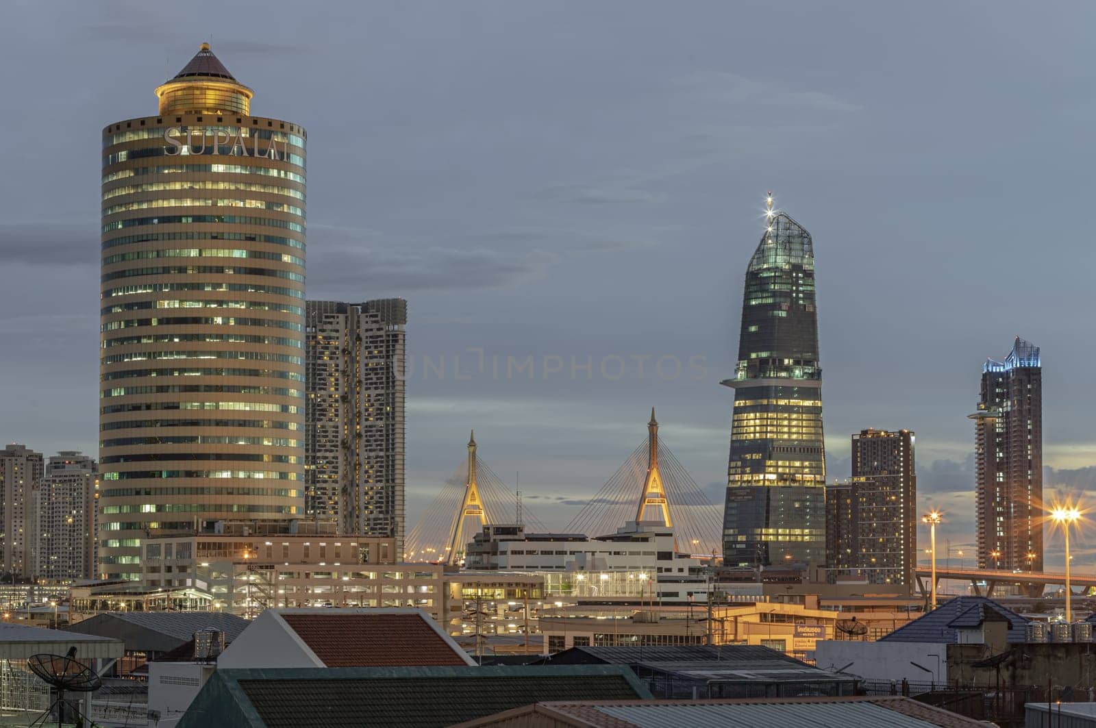 Bangkok, Thailand - Aug 14, 2024 - Night city view with KingBridge tower, Supalai Grand Tower alongside the iconic landmark of Bhumibol Bridge. Stunning At Twilight skyline of bangkok business district with Skyscrapers use it as your wallpaper, poster and banner design, Selective focus.
