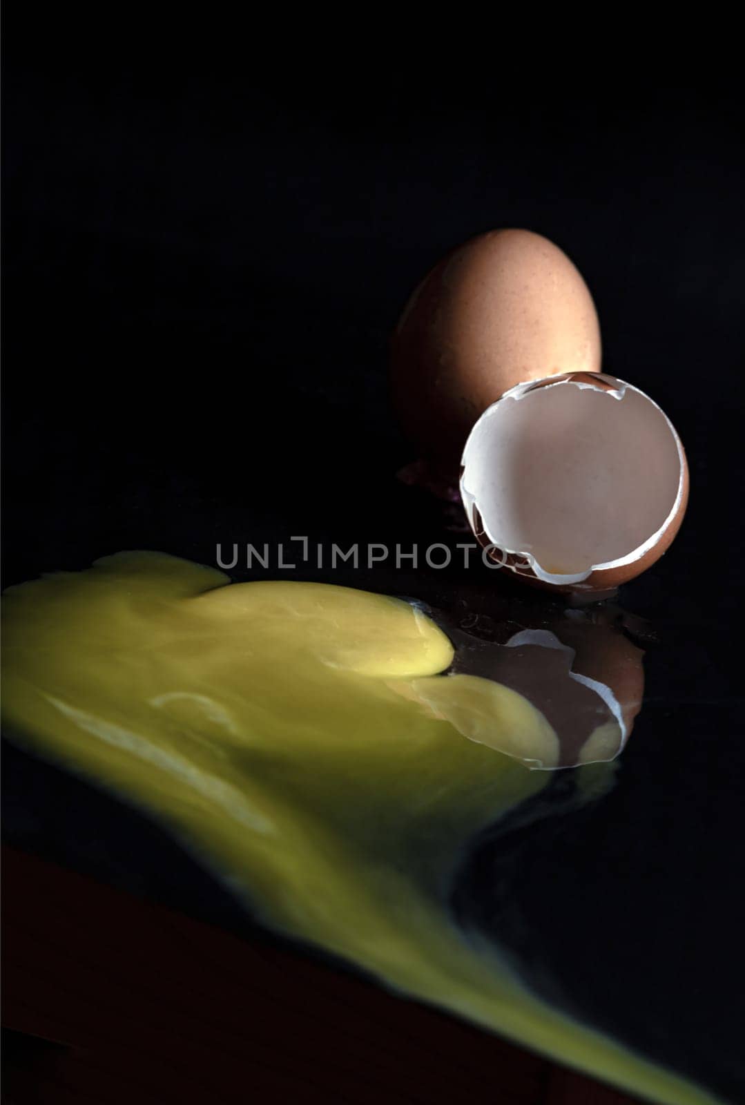 View of Broken egg yolk with Broken raw chicken eggshell in front of Fresh chicken egg (Hen eggs) on Dark background. Fresh eggs from the farmer, Natural organic healthy food concept, Space for text, Selective focus.