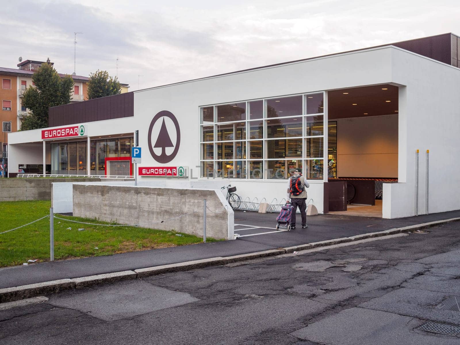Cremona, Italy September 26th 2024 A man is walking away from a eurospar supermarket with a shopping cart after doing his grocery