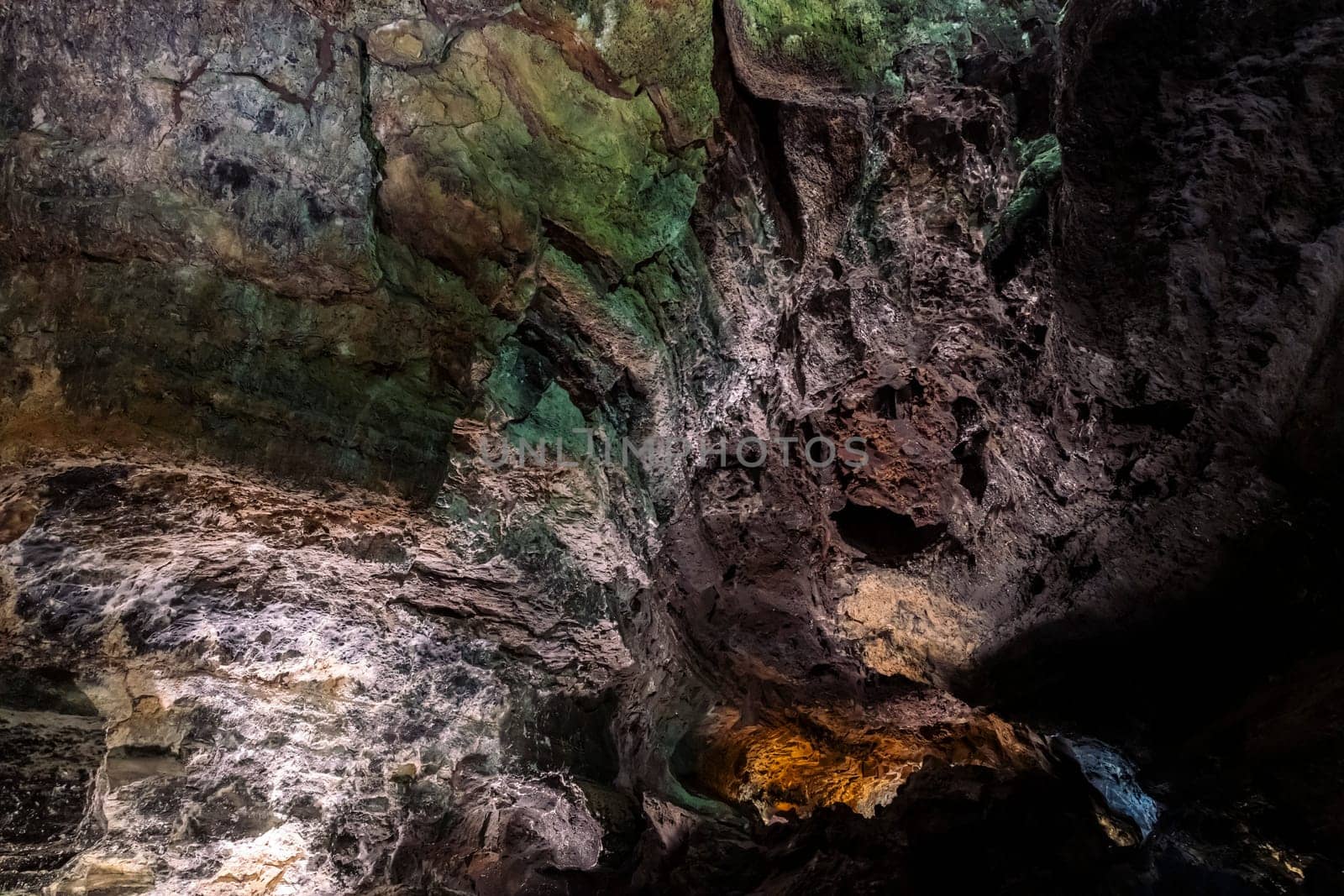 scenic view of majestic cave with different types of minerals and moss on curved rugged surface, concept of nature and geology