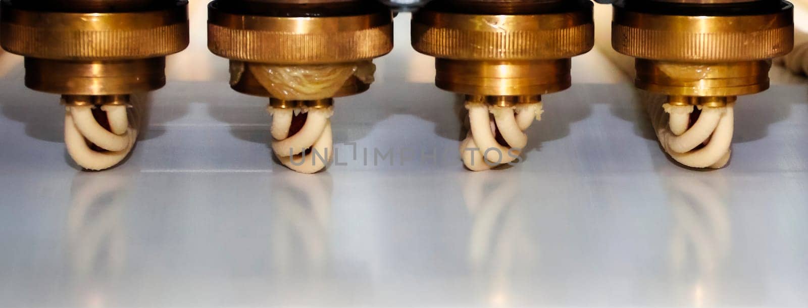 Complex equipment operates to extrude materials with precision, showcasing metal components and a streamlined process inside a busy manufacturing plant.