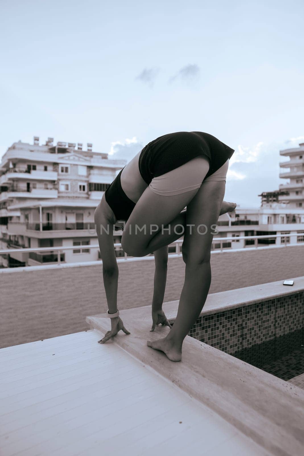 A striking yoga pose being performed on a rooftop, beautifully showcasing flexibility against the urban city backdrop