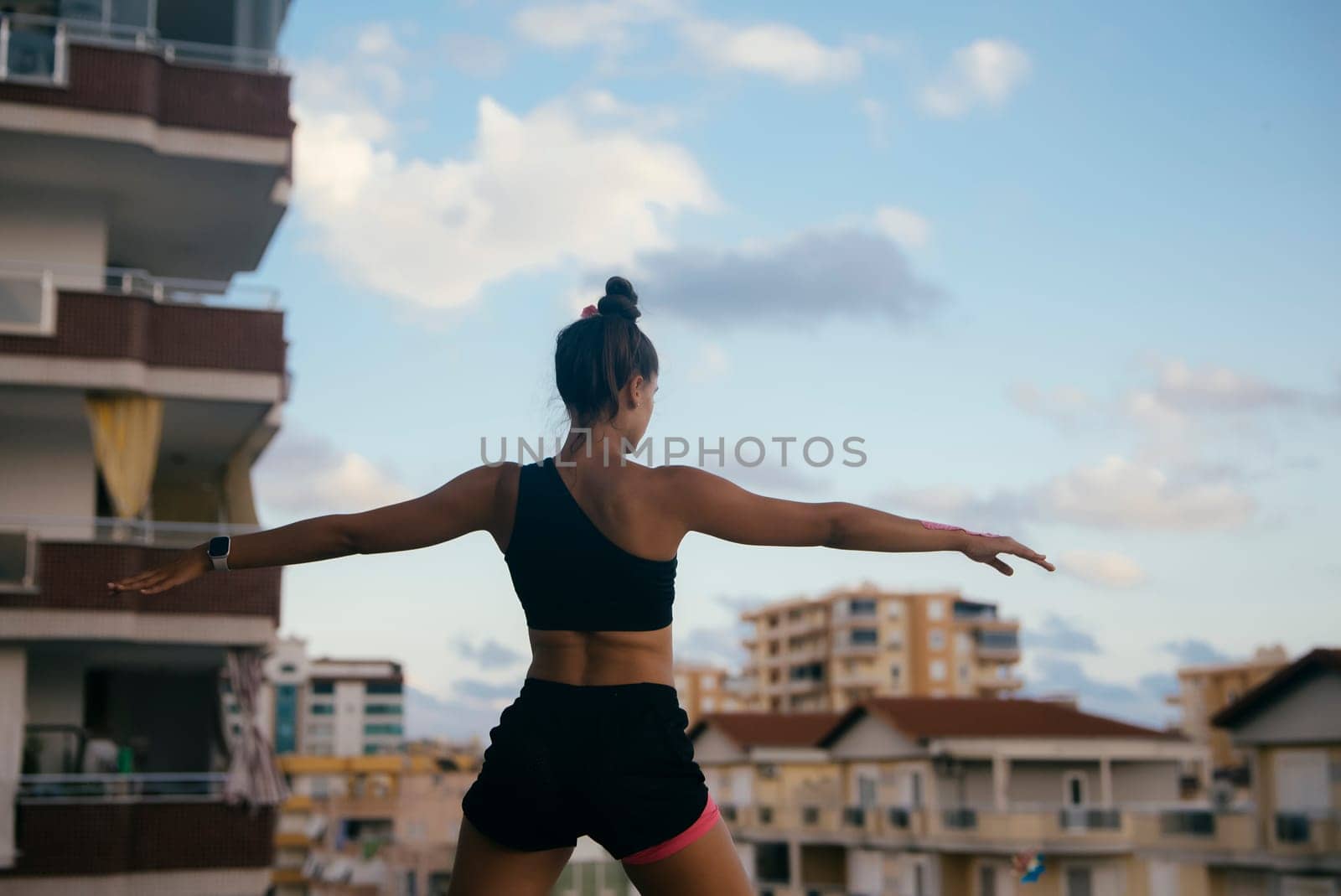 A woman is skillfully practicing yoga on a rooftop, fully enjoying the beautiful, serene city skyline and fresh air