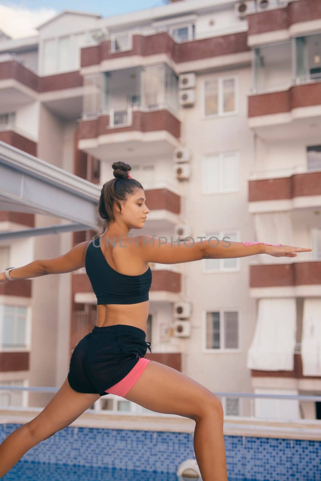 A fit individual gracefully practicing yoga on a stunning rooftop terrace, framed beautifully by urban architecture