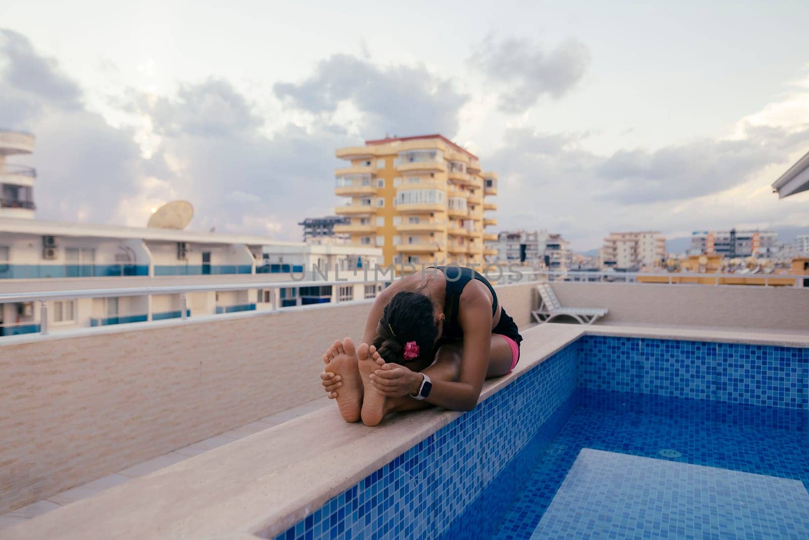 A person is relishing a serene moment spent by the pool located on a beautiful rooftop with a stunning backdrop