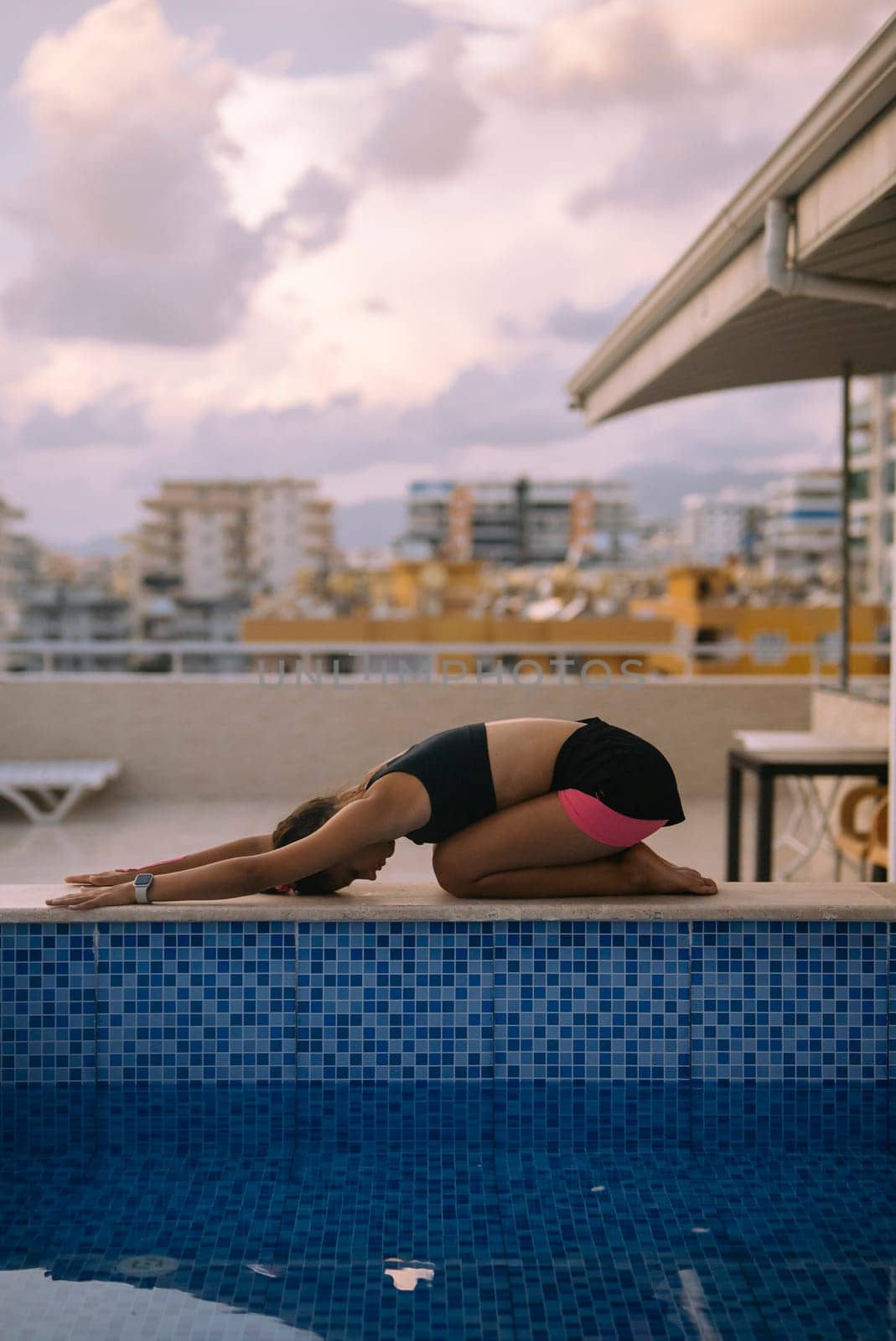 A tranquil yoga pose is gracefully performed by the poolside, beautifully combining mindfulness with relaxation
