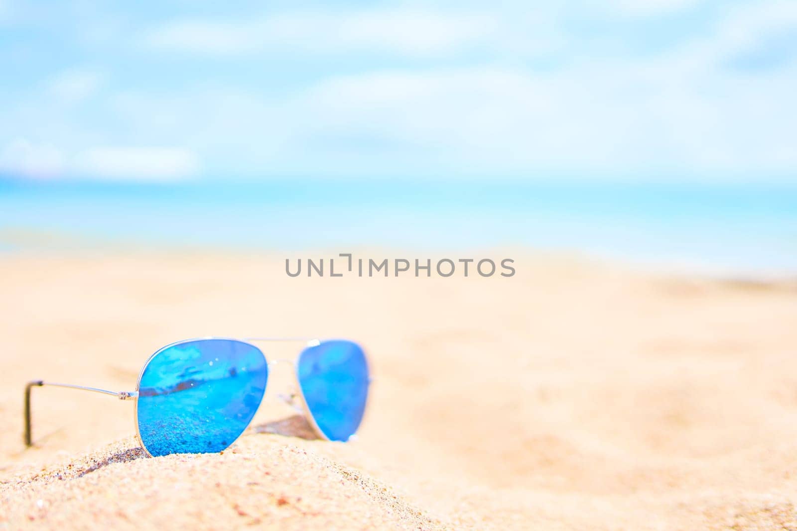 Sunglasses on the beach with ocean and sky on background