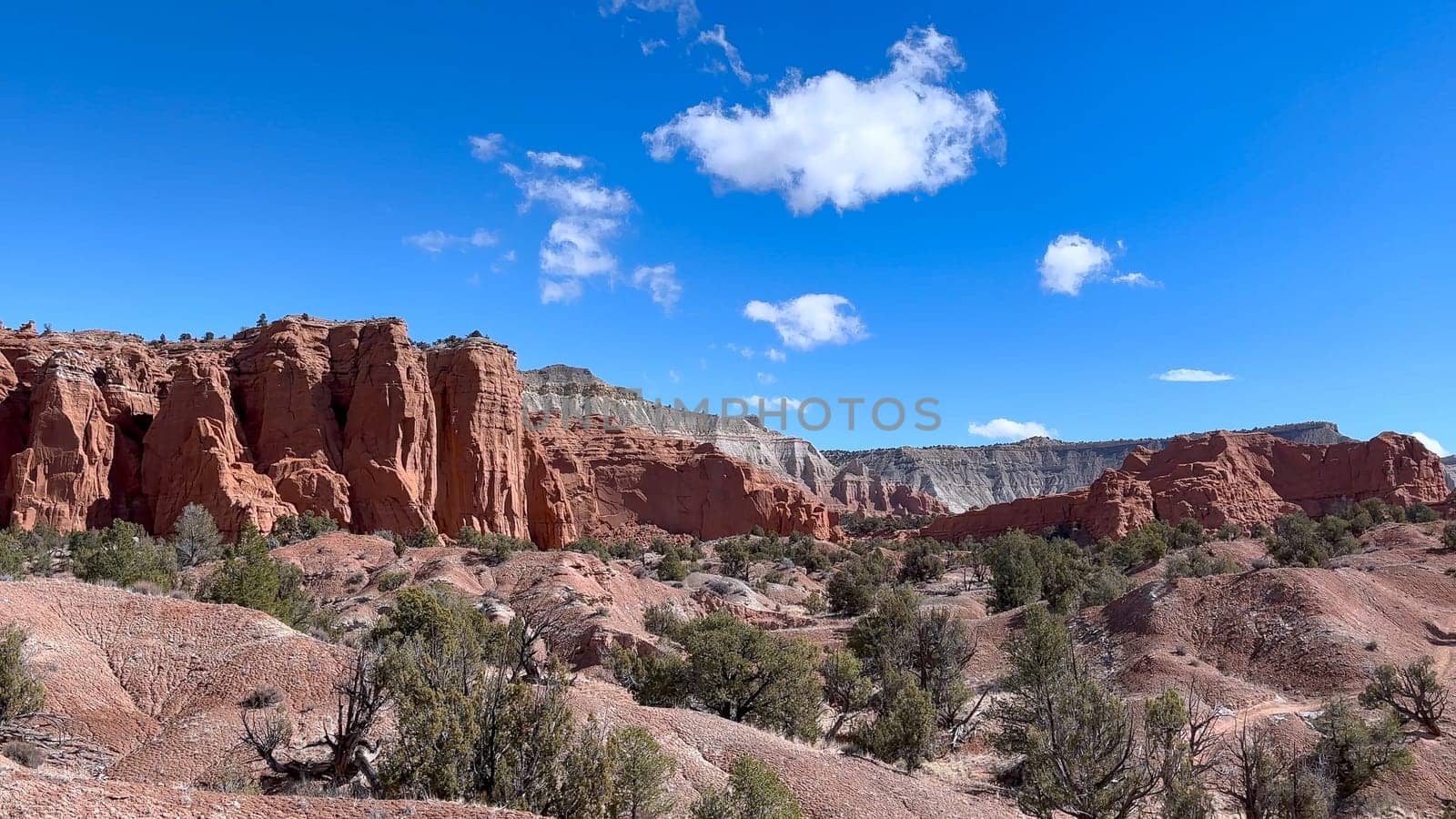 Panoramic view of the red rock formations and desert landscape of Kodachrome Basin State Park in Utah, USA. The blue sky provides a beautiful contrast to the red rocks and green vegetation.