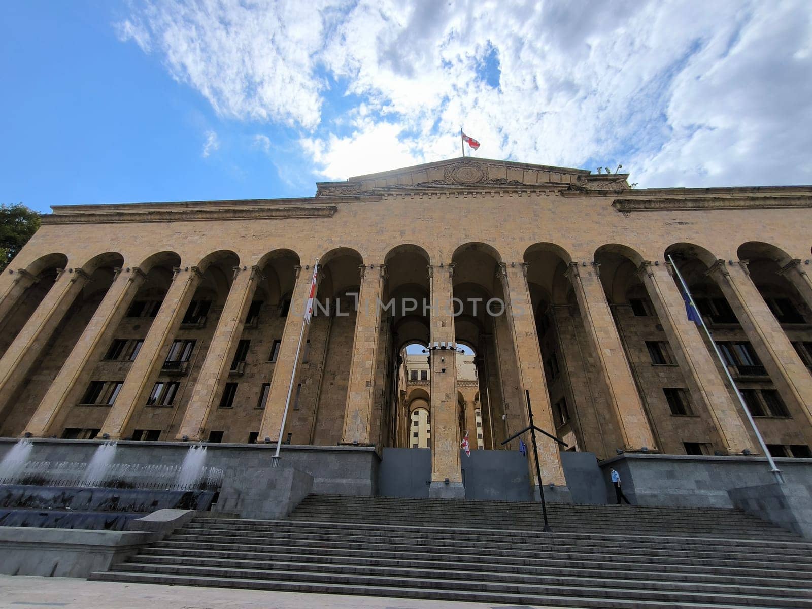 18 August 2024 Tbilisi Georgia modern building in the city center, gray stone stre fontaine, flag. High quality photo