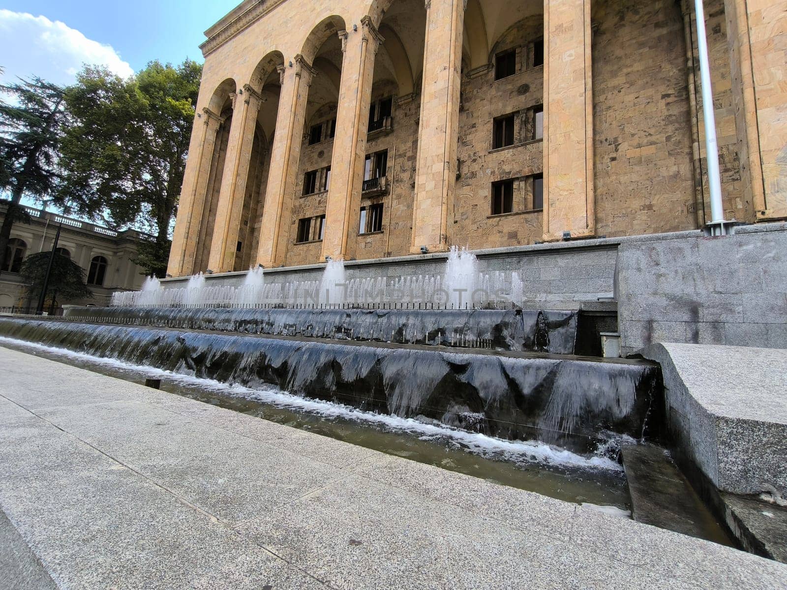 18 August 2024 Tbilisi Georgia modern building in the city center, gray stone stre fontaine, flag. High quality photo