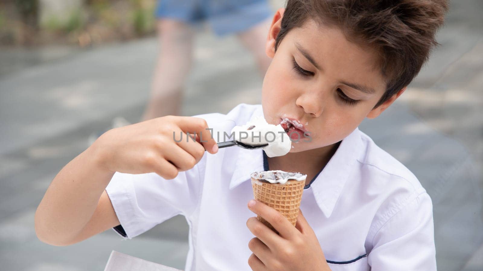 Boy happily eating ice cream on the street, his face covered in chocolate, refreshing dessert during a walk on a summer day, carefree peaceful childhood,