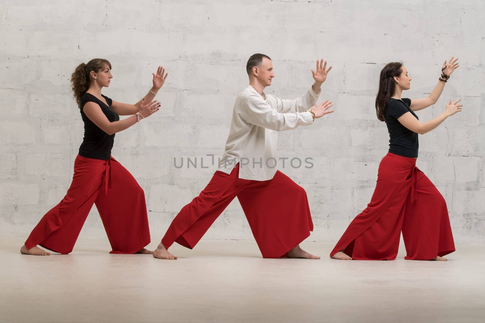Group of women and their male trainer doing yoga exercises against brick wall profile shot
