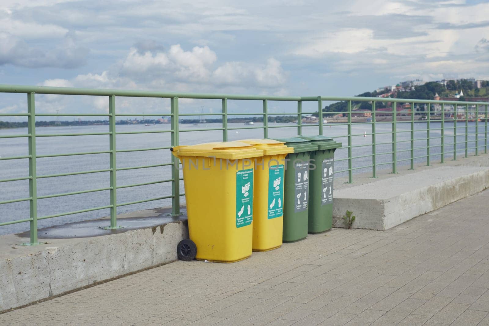 NIZHNY NOVGOROD, RUSSIA-JULY 31, 2024: four plastic garbage cans for sorting garbage on the embankment next to the river.