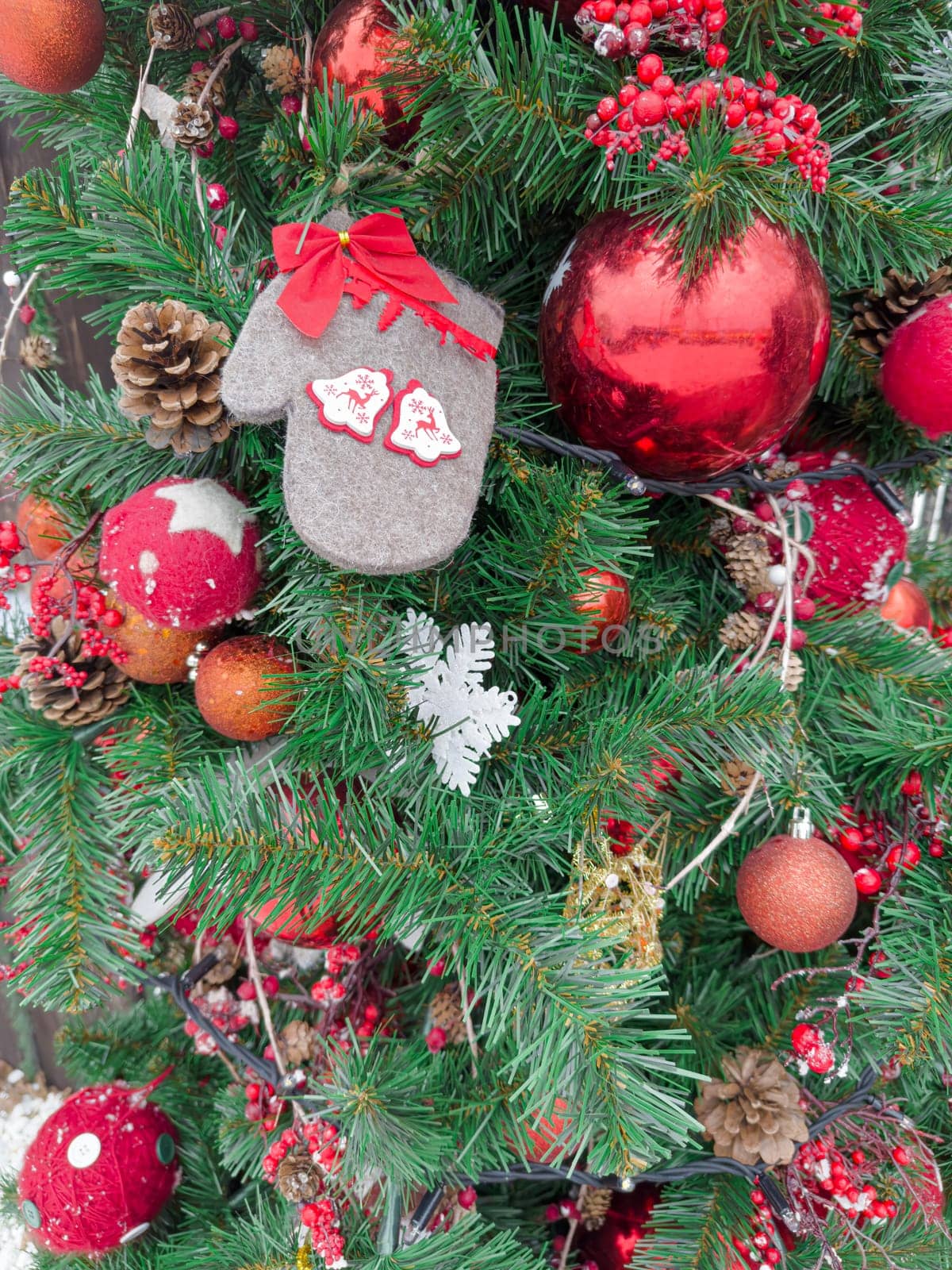 A lively Christmas tree showcases vibrant red ornaments, decorative mittens, and pine cones, creating a joyful atmosphere perfect for the holiday season and festivities.
