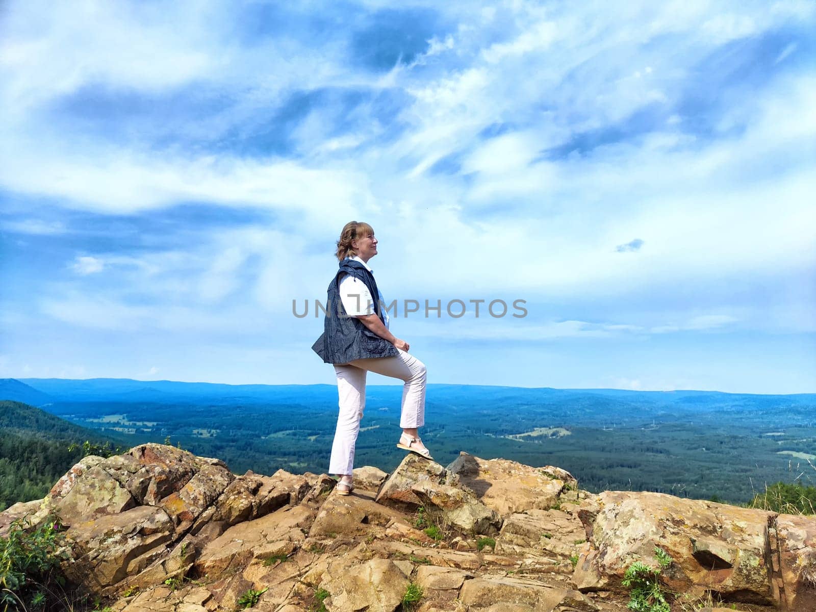 A blogger happily takes a selfie with breathtaking mountain views in the background while enjoying her adventure in nature