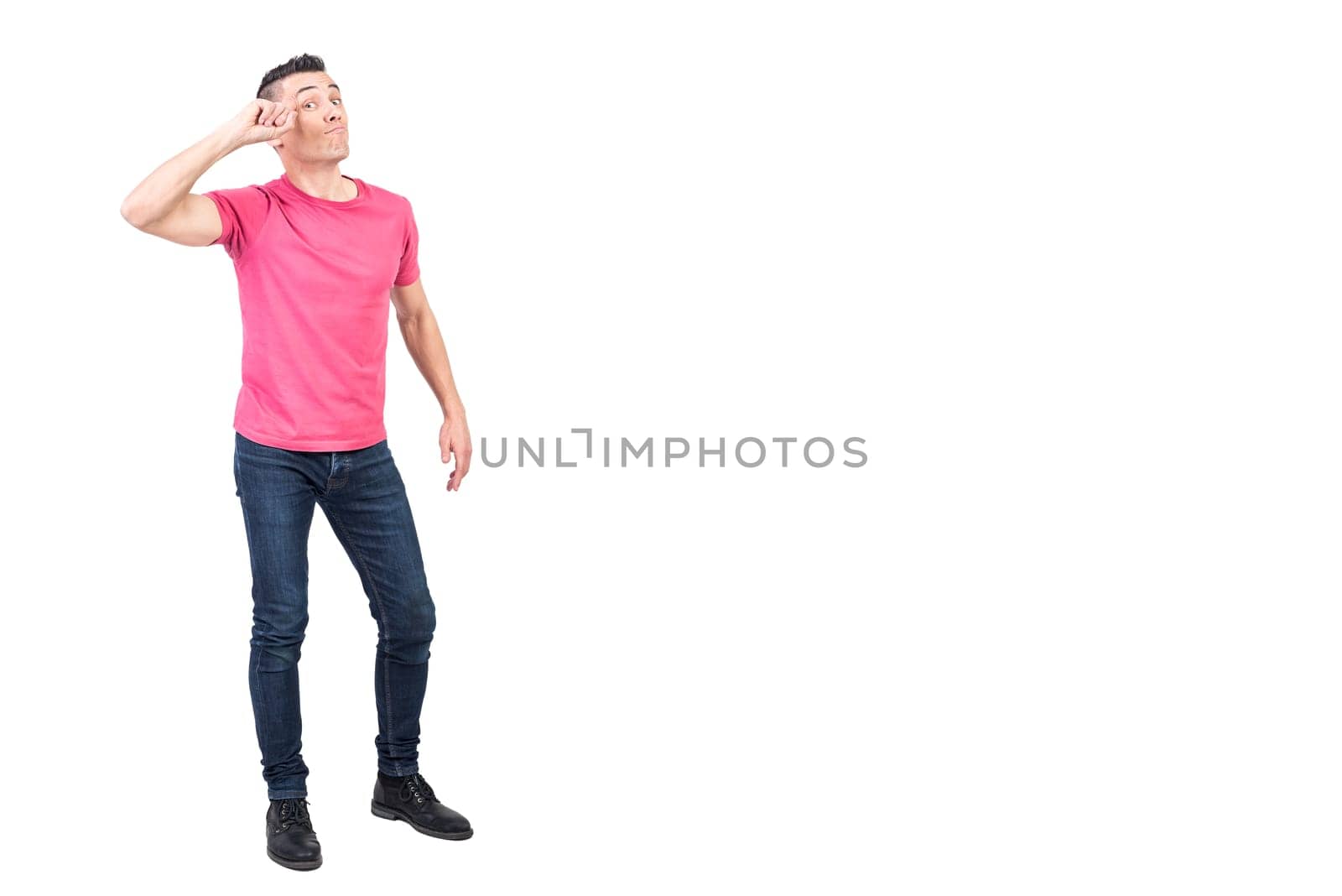 Full body of self assured young male model with dark hair in casual clothes touching forehead and looking at camera against white background
